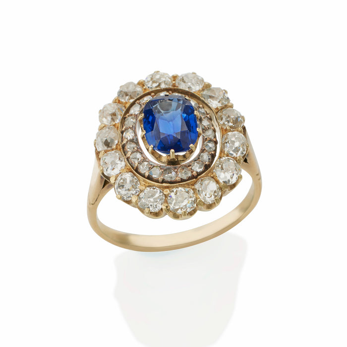 Macklowe Gallery An English Antique 15 karat gold/silver top ring with sapphire and diamonds. The ring centers on a no heat oval-cut sapphire with an approximate weight of .95 carat, 14 old mine-cut diamonds with an approximate total weight of 1.40 carats, and 19 rose-cut diamonds with an approximate total weight of .19 carat.  Designed in a classic oval cluster motif.  